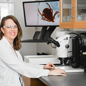 Picture of Emily Owens Pickle (M.P.H, Ph.D.) observing a tick under the microscope in the lab